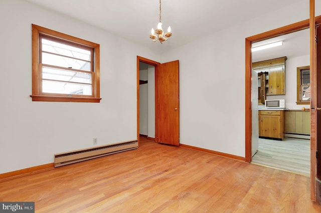 unfurnished bedroom featuring a chandelier, a baseboard radiator, and light hardwood / wood-style flooring