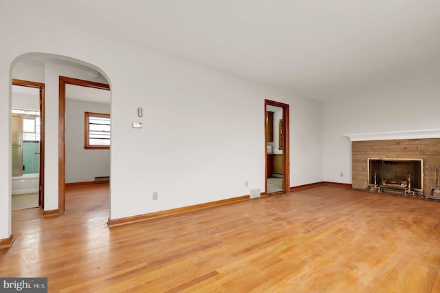 unfurnished living room featuring a stone fireplace and light hardwood / wood-style flooring