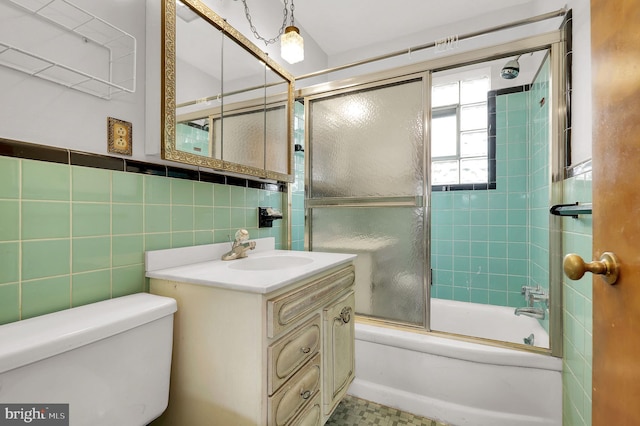 full bathroom with vanity, toilet, combined bath / shower with glass door, and tile walls