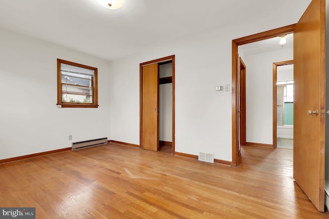 unfurnished bedroom with a closet, a baseboard radiator, and light hardwood / wood-style floors