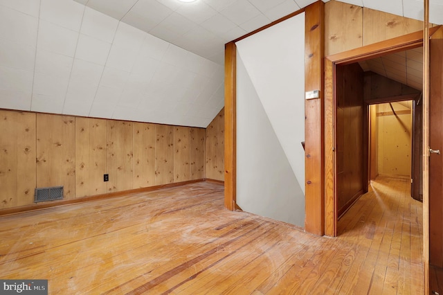 bonus room with wood walls, light hardwood / wood-style floors, and vaulted ceiling