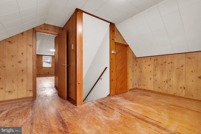 additional living space with hardwood / wood-style flooring, lofted ceiling, and wood walls