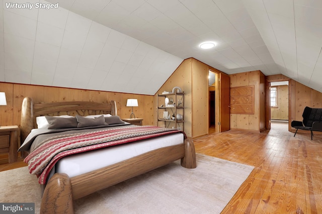 bedroom with hardwood / wood-style flooring, vaulted ceiling, and wood walls