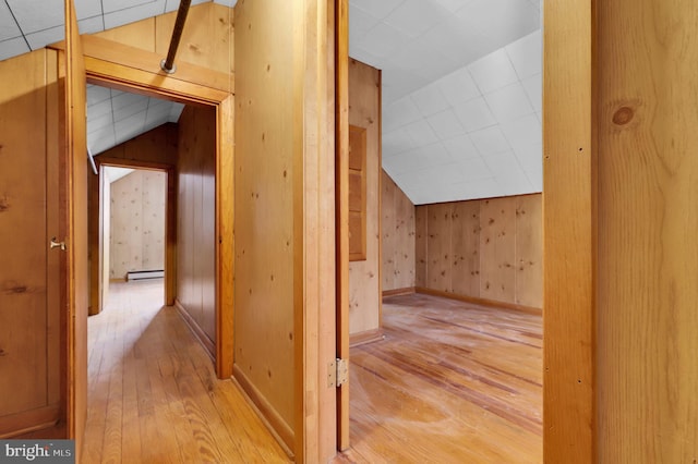 hallway featuring light hardwood / wood-style floors, baseboard heating, lofted ceiling, and wood walls