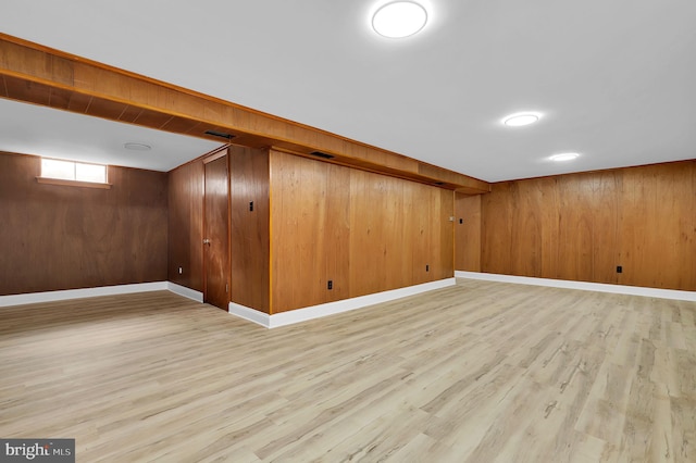 basement featuring wooden walls and light wood-type flooring