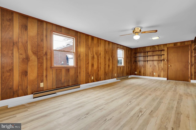 empty room featuring ceiling fan, baseboard heating, wooden walls, and light hardwood / wood-style flooring