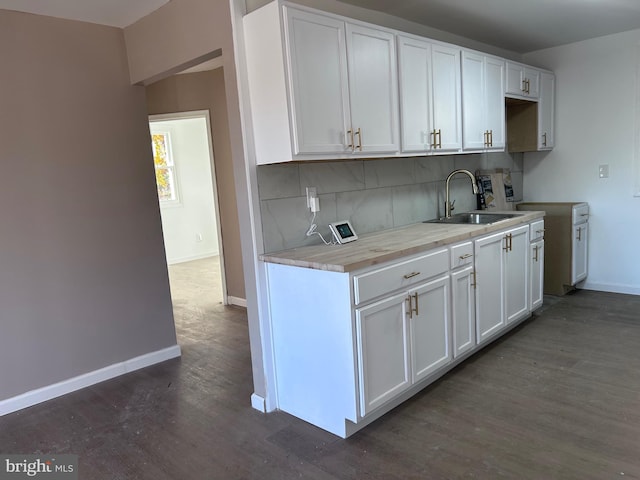 kitchen with decorative backsplash, sink, white cabinetry, and dark wood-type flooring