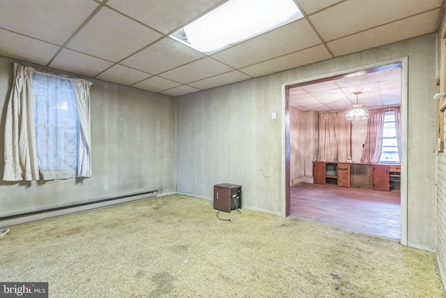 unfurnished room with carpet, a drop ceiling, a chandelier, and a baseboard radiator