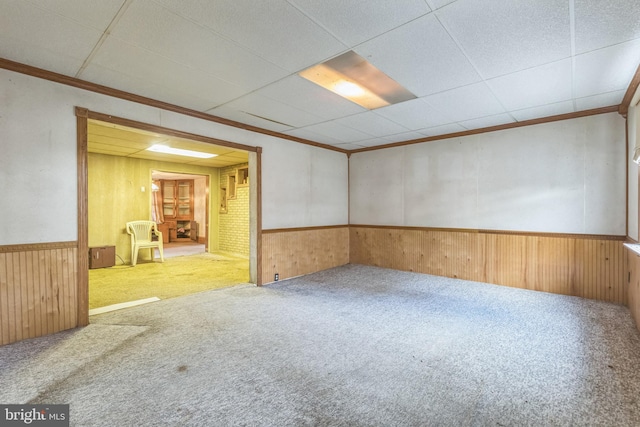 carpeted spare room featuring crown molding and wooden walls