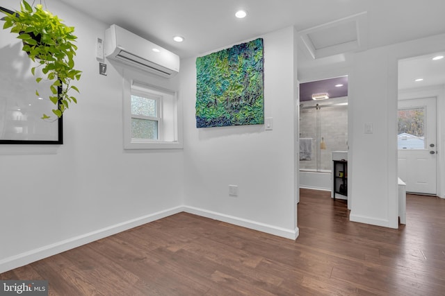 spare room with a wall mounted AC, a healthy amount of sunlight, and dark hardwood / wood-style floors