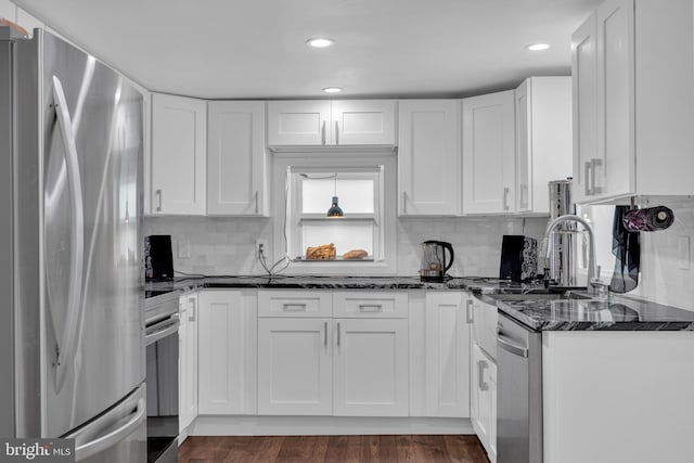 kitchen with decorative backsplash, dark stone countertops, appliances with stainless steel finishes, dark hardwood / wood-style flooring, and white cabinetry