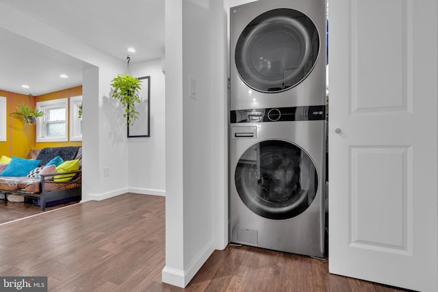 clothes washing area featuring dark hardwood / wood-style flooring and stacked washing maching and dryer