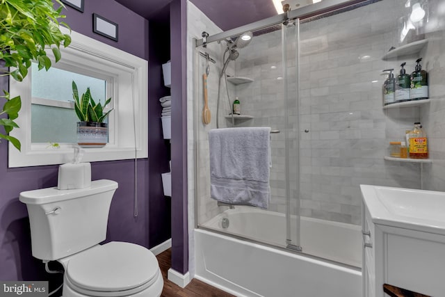 full bathroom featuring shower / bath combination with glass door, vanity, hardwood / wood-style flooring, and toilet