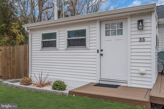 entrance to property featuring a yard and a deck