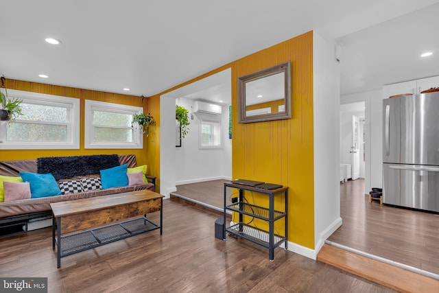 living room featuring a wall unit AC, a healthy amount of sunlight, and dark wood-type flooring