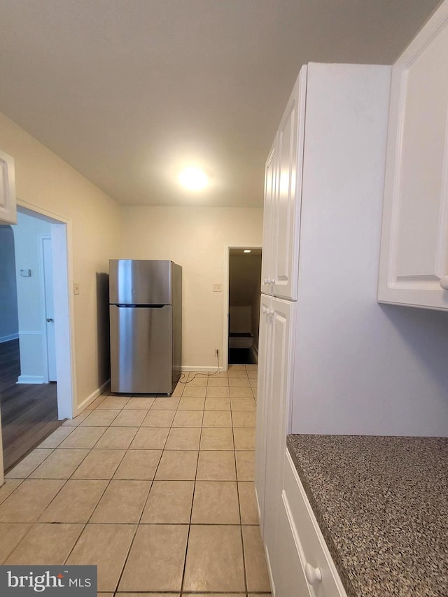 kitchen featuring stainless steel refrigerator, white cabinetry, and light tile patterned floors