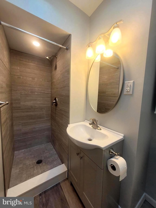 bathroom featuring hardwood / wood-style floors, vanity, and tiled shower