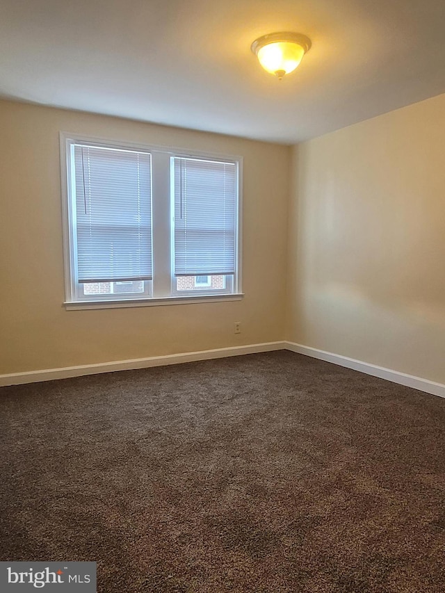 empty room featuring dark carpet and a healthy amount of sunlight