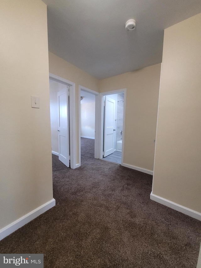 spare room with dark colored carpet