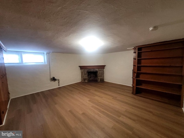 basement featuring a textured ceiling, wood-type flooring, and a fireplace