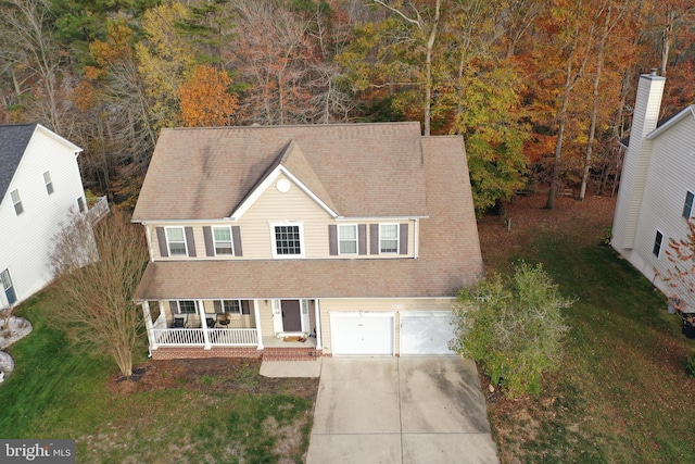 view of front of home featuring a porch, a garage, and a front lawn