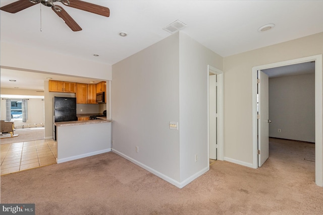 kitchen with ceiling fan, black refrigerator, and light colored carpet