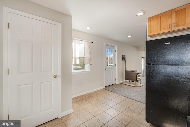 kitchen featuring light tile patterned flooring, black fridge, and a wood stove