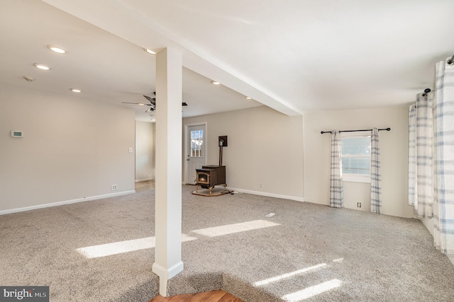 spare room with a wood stove, ceiling fan, and carpet floors