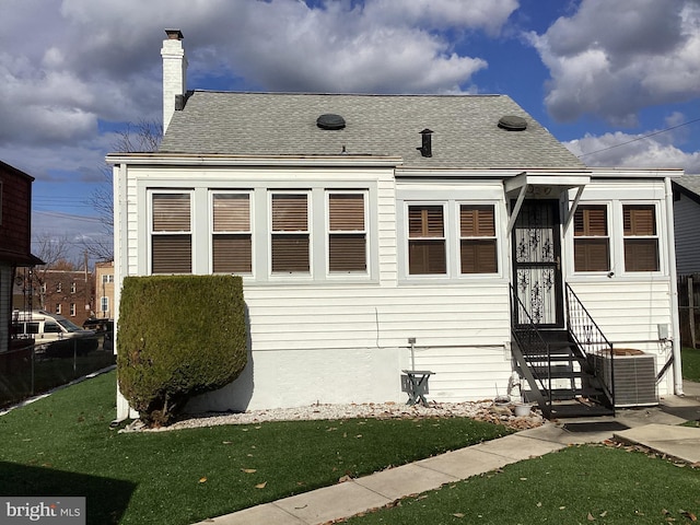 view of front of property with central AC and a front lawn