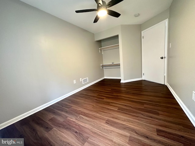 unfurnished bedroom with ceiling fan, dark wood-type flooring, and a closet