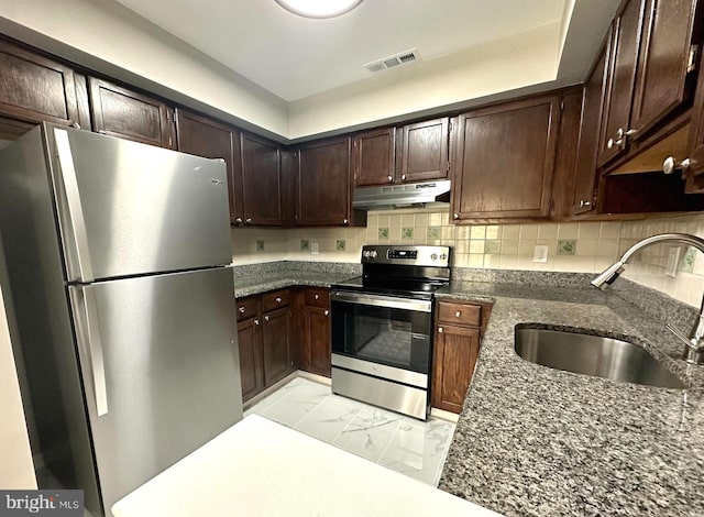 kitchen with decorative backsplash, stainless steel appliances, dark stone counters, and sink