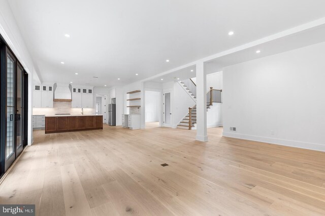 unfurnished living room with light wood-type flooring and sink