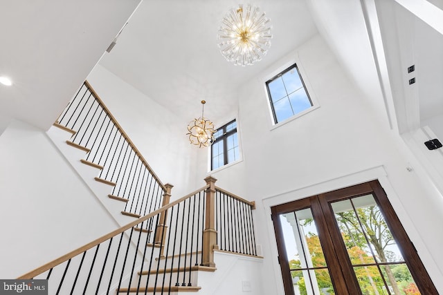 stairs featuring french doors and a notable chandelier