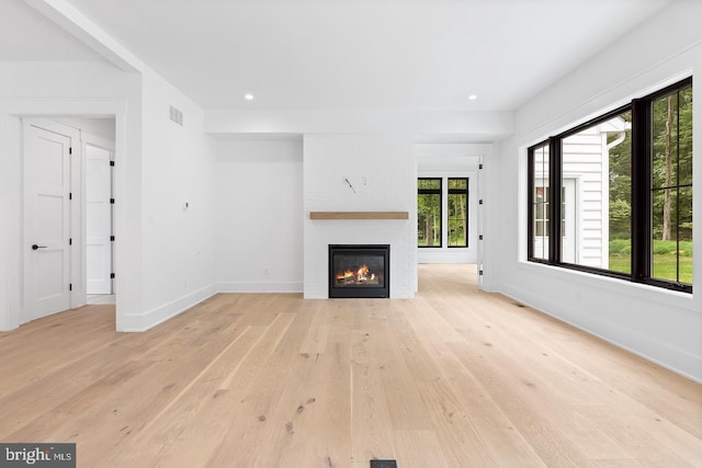 unfurnished living room with a large fireplace and light hardwood / wood-style floors