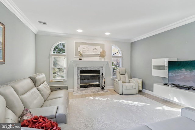 living room with a premium fireplace, crown molding, and light hardwood / wood-style flooring