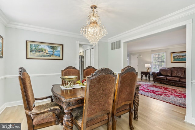 dining room featuring light wood-type flooring, an inviting chandelier, and crown molding