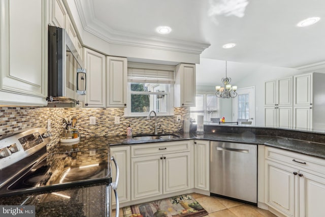 kitchen featuring dark stone counters, sink, decorative light fixtures, stainless steel appliances, and a chandelier