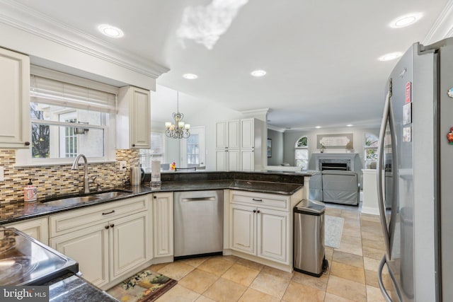 kitchen featuring pendant lighting, backsplash, crown molding, sink, and appliances with stainless steel finishes