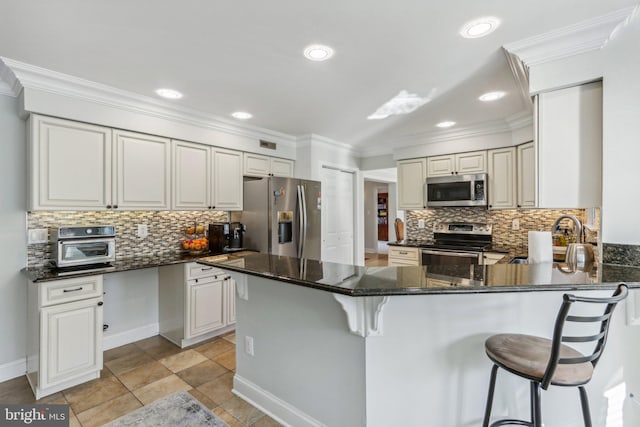 kitchen featuring sink, kitchen peninsula, a breakfast bar area, white cabinets, and appliances with stainless steel finishes