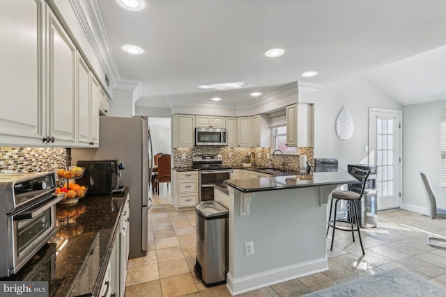 kitchen featuring backsplash, crown molding, sink, appliances with stainless steel finishes, and a breakfast bar area