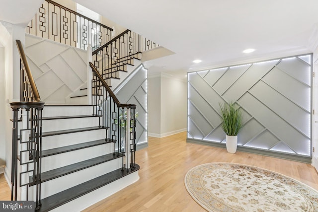 stairs with hardwood / wood-style floors and ornamental molding