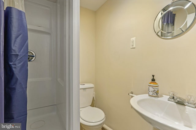 bathroom featuring a shower with shower curtain, toilet, and sink