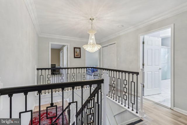 hall with hardwood / wood-style floors, ornamental molding, and a notable chandelier