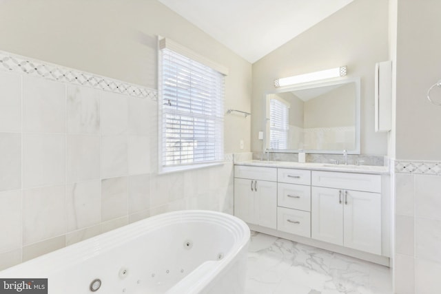 bathroom with vanity, vaulted ceiling, tile walls, and a bathing tub