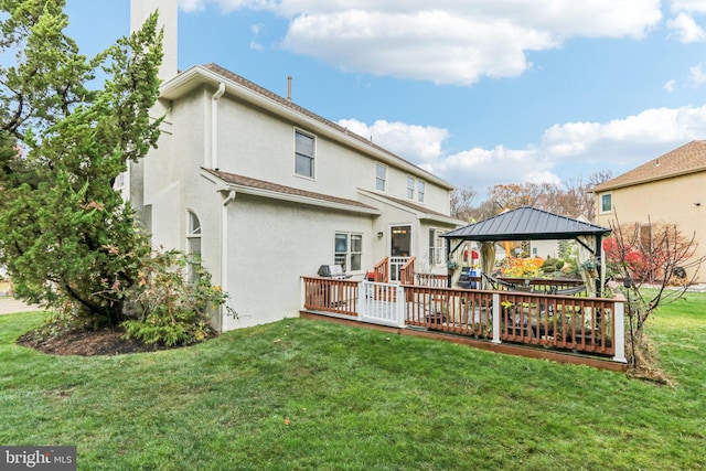 rear view of property featuring a gazebo, a wooden deck, and a lawn