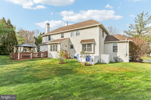 rear view of house featuring a gazebo, cooling unit, and a lawn