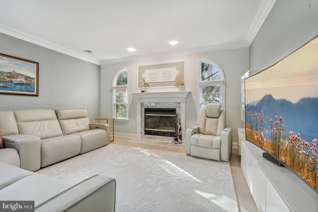 living room with a premium fireplace, crown molding, and light wood-type flooring