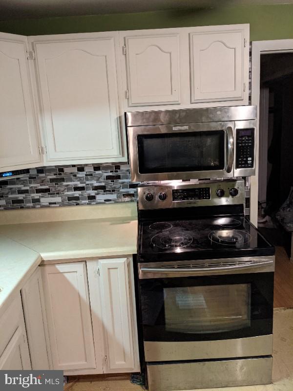 kitchen with decorative backsplash, white cabinetry, and stainless steel appliances