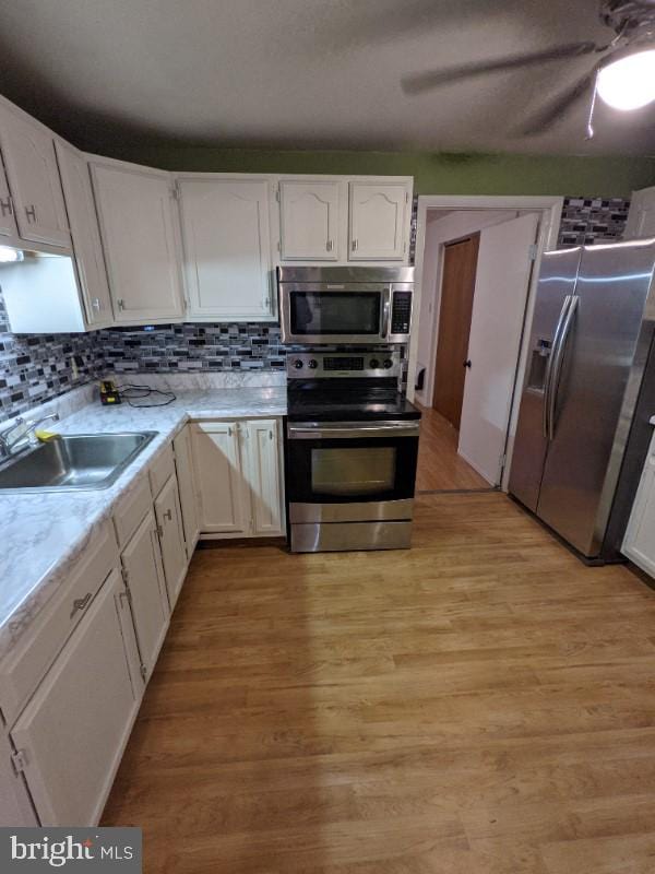 kitchen with white cabinets, light wood-type flooring, sink, and appliances with stainless steel finishes