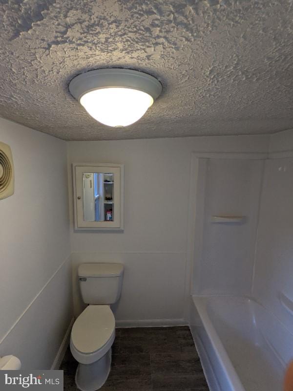 bathroom featuring hardwood / wood-style floors, a textured ceiling, and toilet